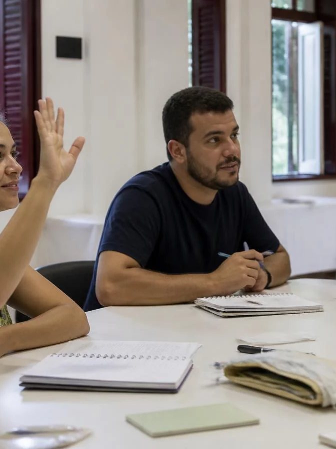 Dupla preparando uma rodada com cadernos abertos e canetas marcadoras sobre a mesa